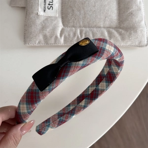 Detail of red plaid headband with black fabric bow and gold 'love' metal charm
