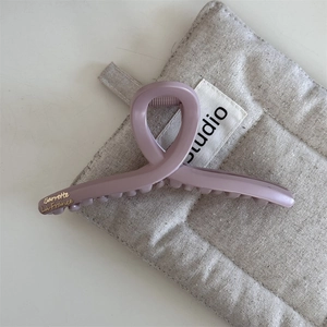 Dettaglio della grande molletta opaca rosa cipria con scritte dorate in stile francese