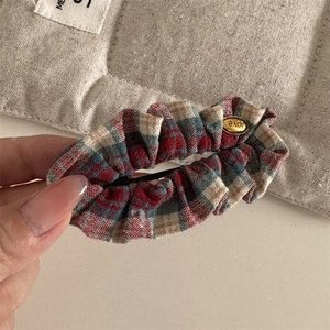 Detail of red and blue plaid fabric hair clip with a gold Love engraved metal charm
