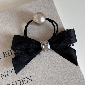 Detailed view of elegant black bow hair tie featuring crystal and faux pearl accents