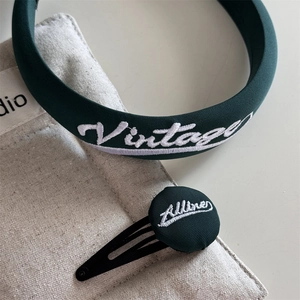 Detail of dark green embroidered vintage headband and button hair clip set texture