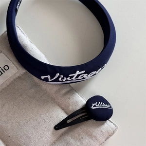 Detail of dark blue fabric headband and BB clip with vintage white embroidery