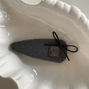 Vue macro d'une pince à cheveux en tissu gris avec nœud noir et plaque en métal vintage