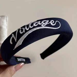 Detailed close-up of navy blue embroidered hair clip with white Vintage lettering texture
