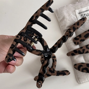 Dettaglio della grande pinza per capelli leopardata che mostra la trama in velluto e la molla
