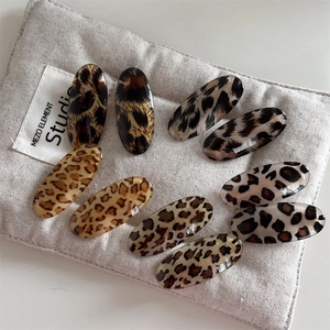 Detailed view of oval leopard print resin hair clips on a soft linen textured background
