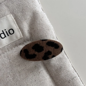 Macro scatto della grande molletta per capelli leopardata su sfondo di lino testurizzato