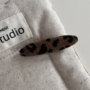 Dettaglio di un fermaglio per capelli in tessuto leopardato su tela color beige