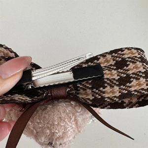 Détail montrant la pince à bec de canard en métal et la structure du clip ours en peluche