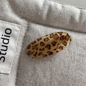 Close-up of vintage leopard print resin hair clip on a minimalist canvas background