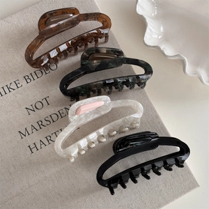 Detail view of four large acetate hair claws in tortoise shell and marble patterns