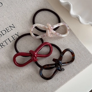 Detailed close-up of acetate bow hair ties in red, tortoiseshell, and marble patterns
