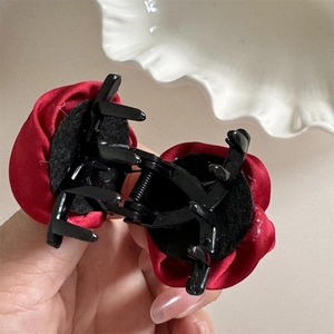 Close-up of red satin rose hair claw clip showing the black non-slip inner mechanism