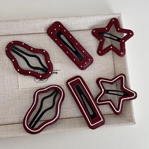 Burgundy polka dot leather hair clips set in star and wave shapes on display tray