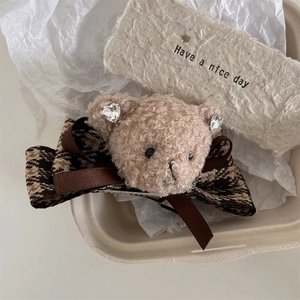 Détail d'une pince à cheveux ours en peluche avec nœud à carreaux et strass en cœur