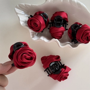 Macro detail of elegant red satin rose hair claw clips resting on a shell tray