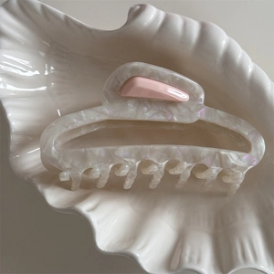 Detailed macro view of French acetate hair claw with iridescent texture in a ceramic bowl