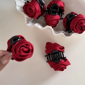 Detailed view of dark red satin rose hair claw with elegant fabric petals and a black base