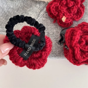 Dettaglio di fermaglio per capelli a rosa rossa all'uncinetto e elastico con etichetta fatta a mano