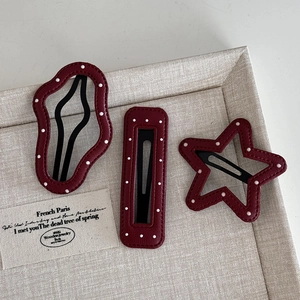 Retro red polka dot leather hair clips set with star and geometric shapes on fabric