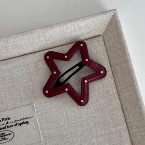 Macro view of red polka dot star hair clip showing fine stitching on linen tray