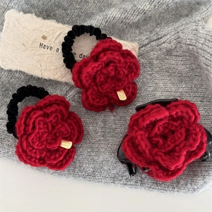 Dettaglio dei fermagli per capelli a rosa in maglia rossa con eleganti etichette dorate