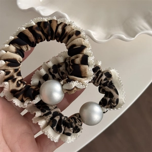 Gros plan de chouchous léopard avec bordure en dentelle blanche et détail perle