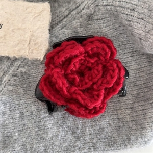 Macro di molletta per capelli con fiore all'uncinetto rosso e dettaglio logo dorato