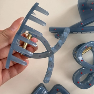 Macro view of blue hair claw clip with red polka dots and golden metal spring mechanism