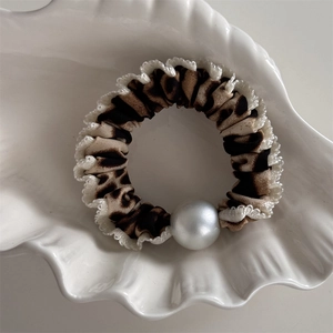 Détail du chouchou à motif léopard avec bords froufrous blancs et perle brillante