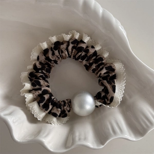 Gros plan sur chouchou léopard avec bordure en dentelle blanche et détail grande perle