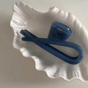 Detail of blue hair claw clip with red polka dots on shell plate showing the metal spring