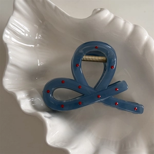 Close-up of matte blue claw clip with red dots on a white shell decorative tray