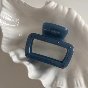 Detailed close-up of a blue hollow rectangle hair claw with delicate red dot accents