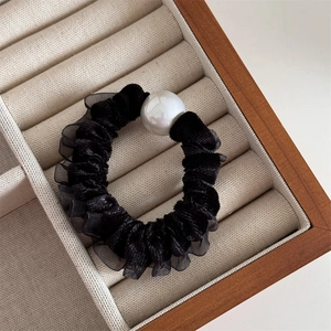 Close-up of black velvet scrunchie with lace trim and a large white pearl bead