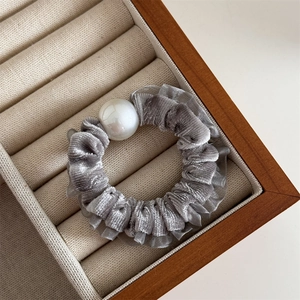 Detail of grey velvet hair scrunchie with lace trim and large faux pearl decoration