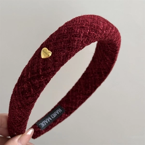 Close-up of wine red textured headband with golden heart buckle and hand made label