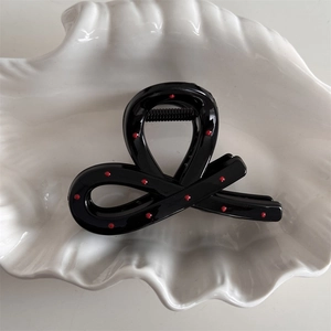 Macro detail of the glossy black hair claw with red polka dots and secure grip teeth