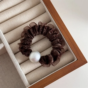 Detail view of velvet scrunchie with large pearl in a wooden display box