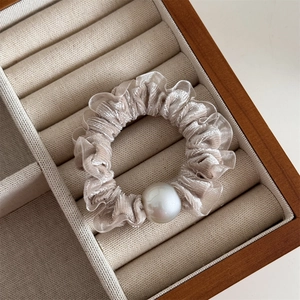 Close-up of champagne velvet scrunchie with lace edge and a large decorative white pearl