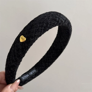 Close-up of black tweed wide headband with a golden heart charm and handmade label tag