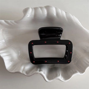 Close-up of a black rectangular hair claw clip with red polka dots on shell tray