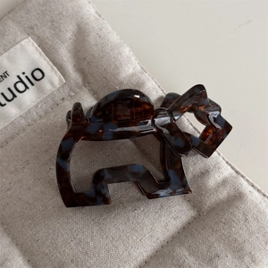 Detail van een haarclip in hondenvorm van schildpad-acetaat met blauwe accenten