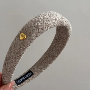 Close-up of beige textured plaid headband with gold heart buckle and handmade label