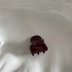 Dettaglio della molletta per capelli in acetato rosso scuro con scritta oro Handmade