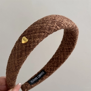 Close-up of brown tweed headband with golden heart button and luxury woven texture