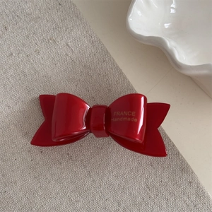 Detail of red acetate bow hair clip with gold France Handmade logo engraving