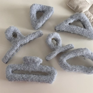 Détail de diverses pinces à cheveux géométriques en peluche grise au fini doux