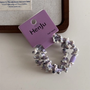 Detailed close-up of a purple braided hair band with beads and knitted texture