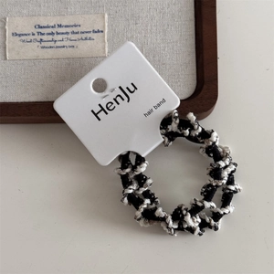 Detail shot of black and white woven elastic hair bands on a rustic wooden tray